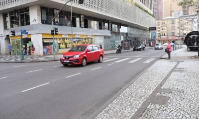 Imagem mostra uma rua e um carro na cor vermelha passando