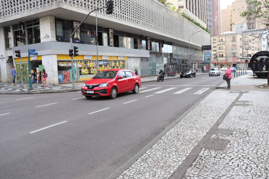 Imagem mostra uma rua e um carro na cor vermelha passando