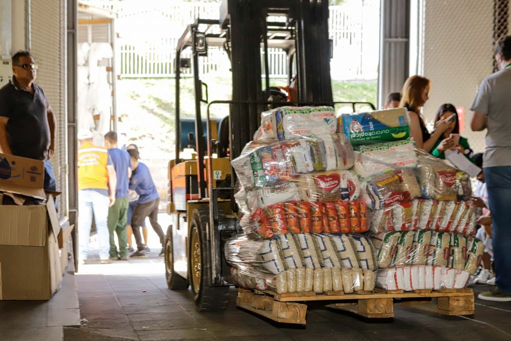 Diversos sacos de donativos sendo carregados por uma empilhadeira.