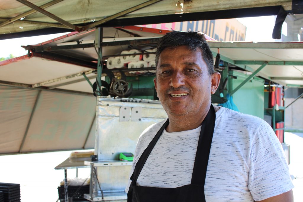 Comerciante Irineu Gonçalves usando uma blusa branca com riscos e avental preto