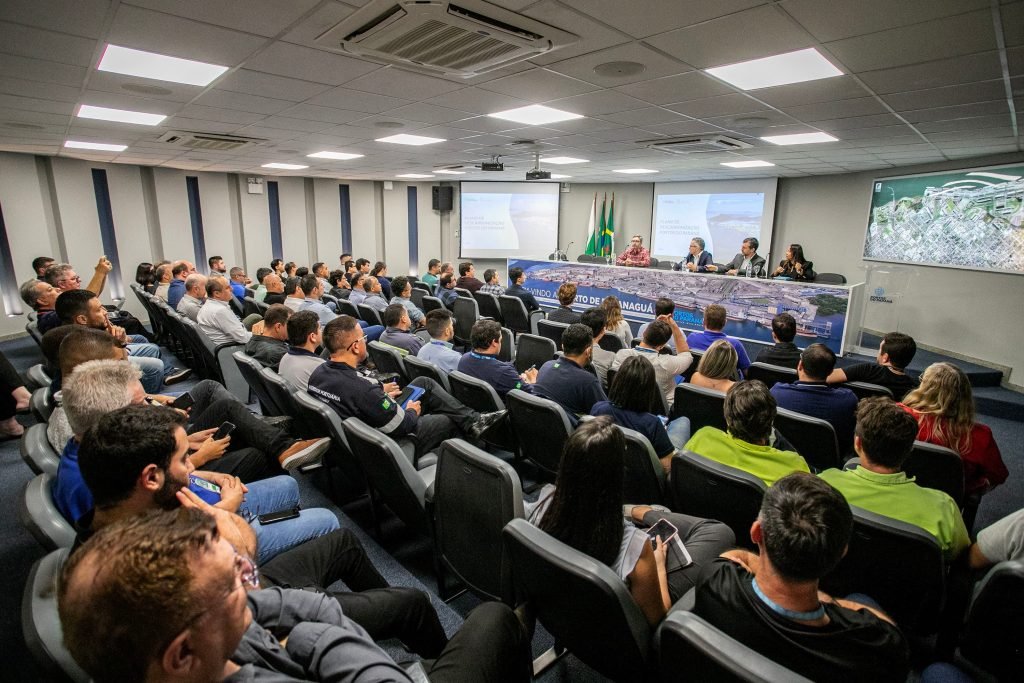 Diversas pessoas em uma palestra sobre o plano de descarbonização da Portos do Paraná, reunidas em uma sala.