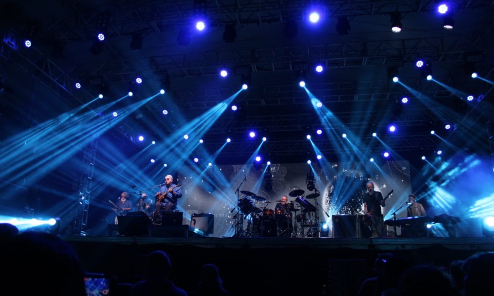 Imagem mostra a banda paralamas do sucesso em seu show em matinhos, a banda está em cima do palco, com diversas luzes no tom azul