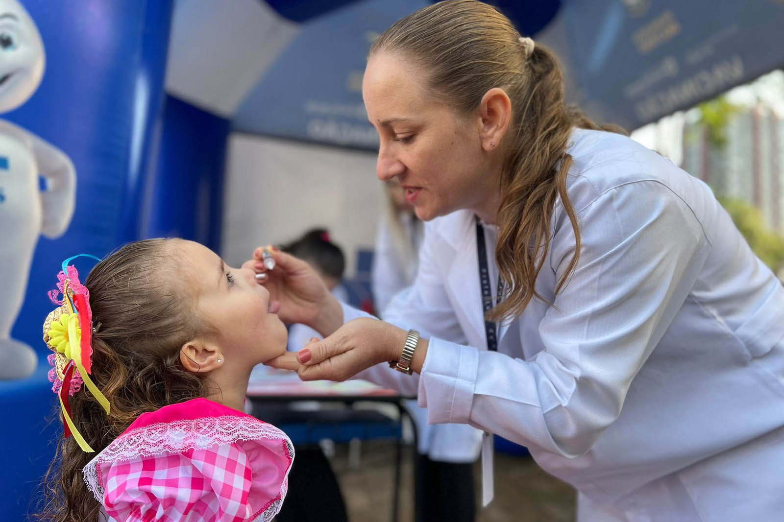 Imagem mostra enfermeira vacinando uma criança contra a poliomielite