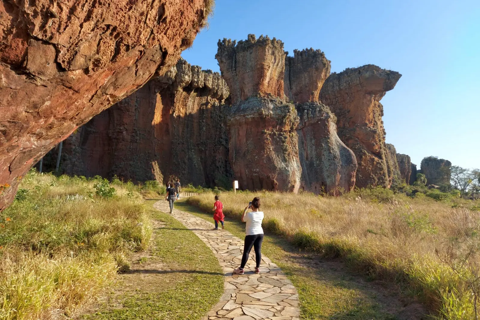 Caminho entre as formações rochosas no Cerrado, com pessoas explorando a natureza em um dia ensolarado, ideal para ecoturismo. Turismo no Paraná cresce quase o triplo da média nacional entre janeiro e outubro