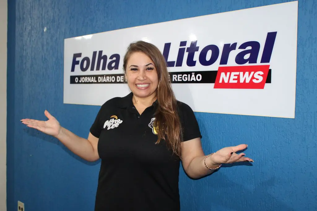 Mulher sorridente em frente ao logo do jornal Folha Litoral, com as mãos abertas demonstrando alegria e simpatia. A imagem transmite a essência de um ambiente de comunicação. Banda Manga Lee mostra que tem um lugar especial no coração dos cidadãos do Litoral do Paraná