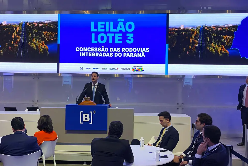 Imagem do leilão Lote 3 referente à concessão das rodovias integradas do Paraná, com um apresentador e público atento.