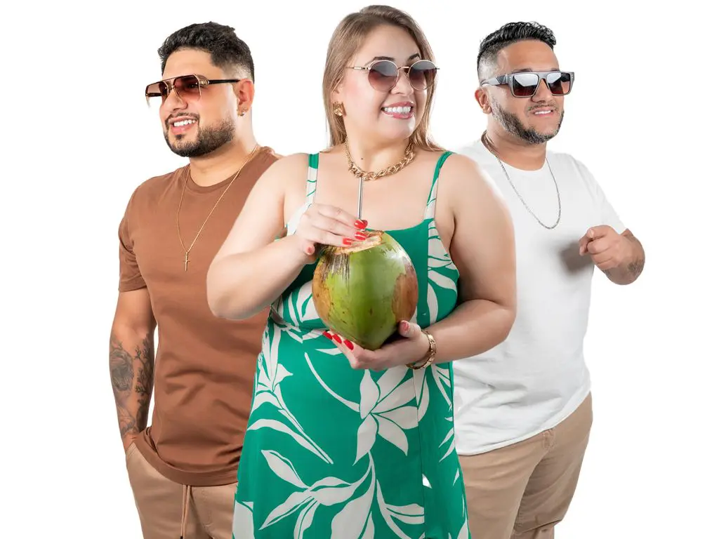 Três pessoas sorrindo em um fundo branco, vestindo roupas de verão, segurando um coco. Uma mulher usa um vestido verde enquanto os homens usam camisetas. Banda Manga Lee mostra que tem um lugar especial no coração dos cidadãos do Litoral do Paraná