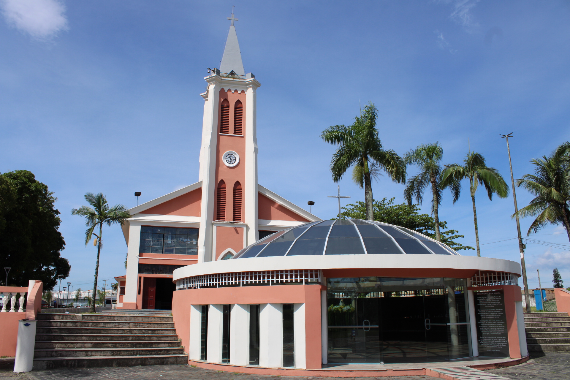 Igreja com torre e cúpula, em um dia ensolarado, cercada por palmeiras e árvores, ideal para visitas e cultos religiosos. Santuário do Rocio recebe imagem peregrina do Divino Pai Eterno no dia 26 de janeiro