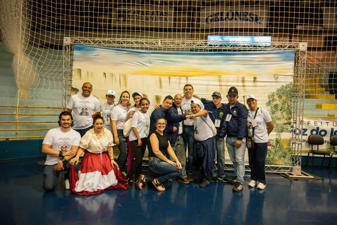 Grupo de pessoas sorrindo em um evento, com destaque para a diversidade e camaradagem. Ambiente festivo e vibrante, com fundo decorativo. Patrocínio de Itaipu na área de esportes beneficia 90 entidades do PR e MS