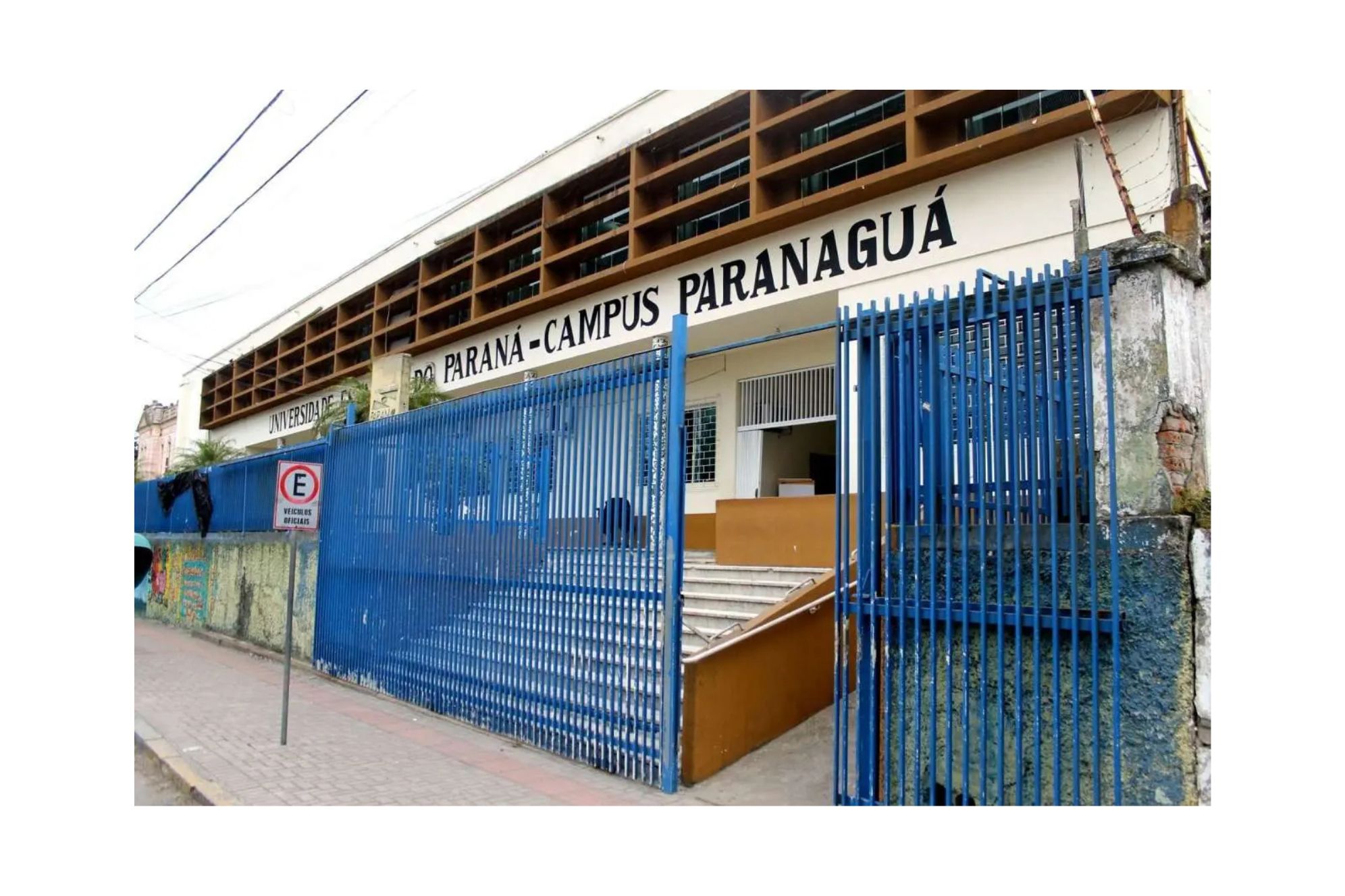 Fachada da Universidade do Paraná, Campus Paranaguá, com portão azul e escola em destaque. Local ideal para educação na região. Unespar abre inscrição para processo seletivo de vagas ociosas