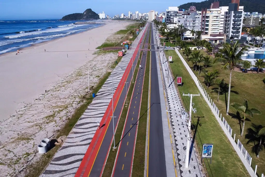 Vista aérea da orla com a praia e calçadão, destacando a faixa de ciclistas e pedestres em ambiente urbano. Nova infraestrutura das praias paranaenses impressiona turistas estrangeiros
