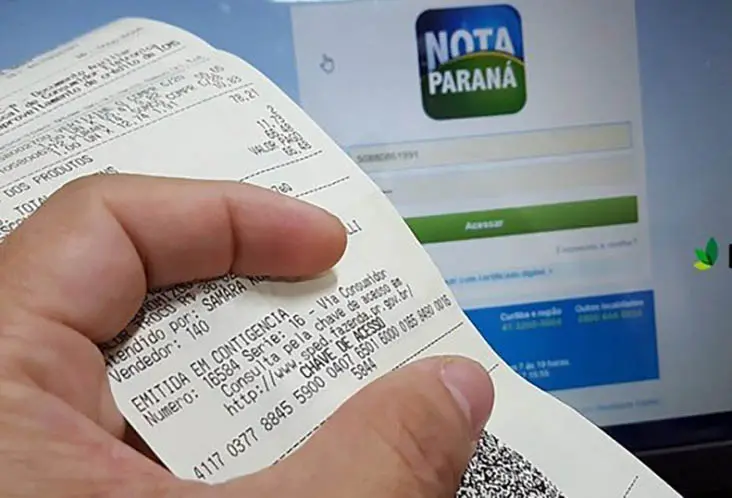 Imagem de uma mão segurando um comprovante de compra, exibindo informações relevantes sobre a Nota Paraná, com a página de acesso ao sistema ao fundo. Campeões do Nota Paraná: de onde são os 10 maiores ganhadores do programa