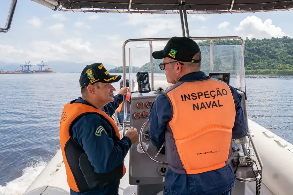 Imagem de dois oficiais da marinha brasileira em um barco, realizando inspeção naval com equipamentos modernos em um ambiente marítimo. Fiscalização marítima é realizada nos portos paranaenses
