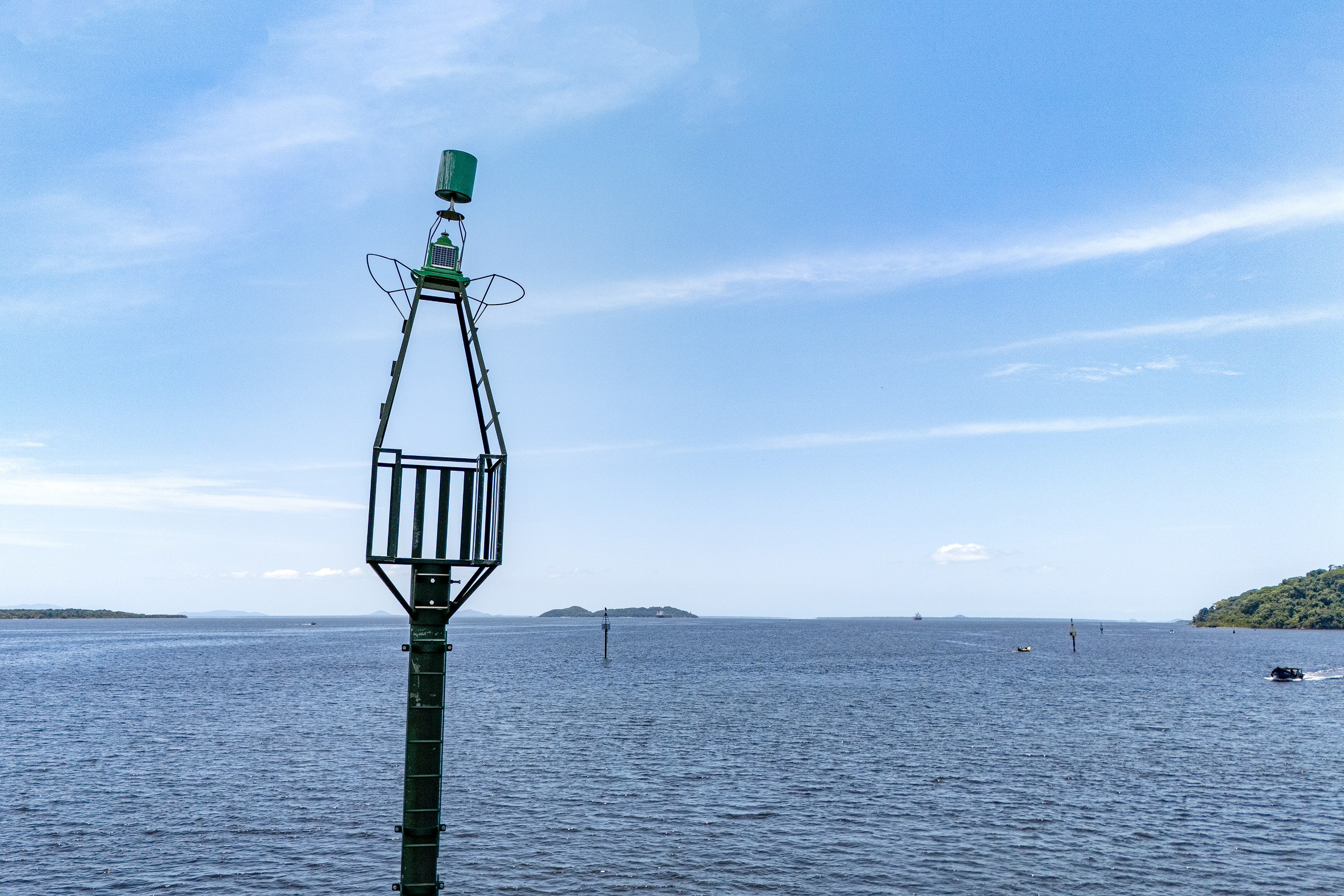 Farol marítimo em meio a um vasto corpo d'água, sob um céu azul claro, ideal para navegação segura e orientação aos barcos. Ilha do Mel vai ganhar nova sinalização náutica no acesso a Nova Brasília e Encantadas