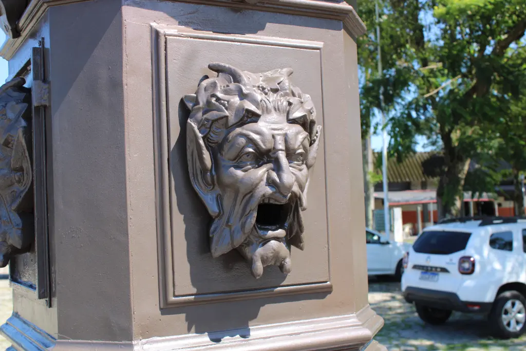 Detalhe de uma fonte antiga com figura esculpida representando um rosto grotesco. Essa escultura é parte de um monumento icônico da cidade. Chafariz do Outono: Conheça a importância histórica do monumento de Paranaguá