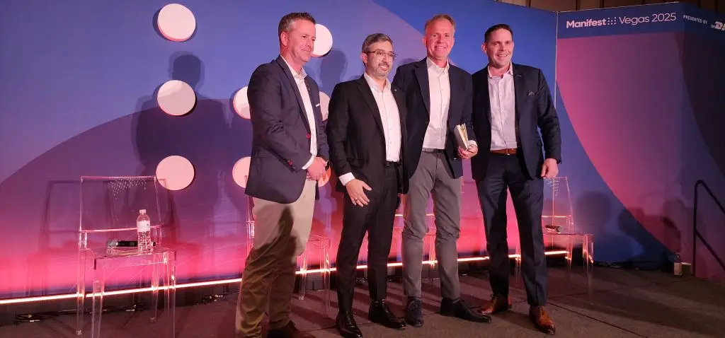 Quatro homens em um evento, posando juntos em um fundo colorido com o nome Manifest 2025 ao fundo, destacando-se a importância da colaboração no cenário de negócios. Portos do Paraná é única empresa portuária brasileira convidada em evento internacional
