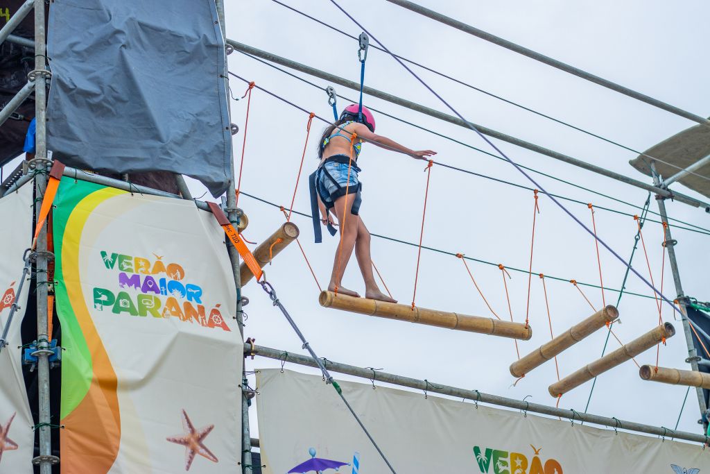 Gente se divertindo na praia com barracas coloridas ao fundo, mostrando um evento animado ao ar livre, cheio de tratamento acolhedor e atividades de lazer. Postos fixos do Verão Maior Paraná encerram atividades com 2,4 milhões de atendimentos
