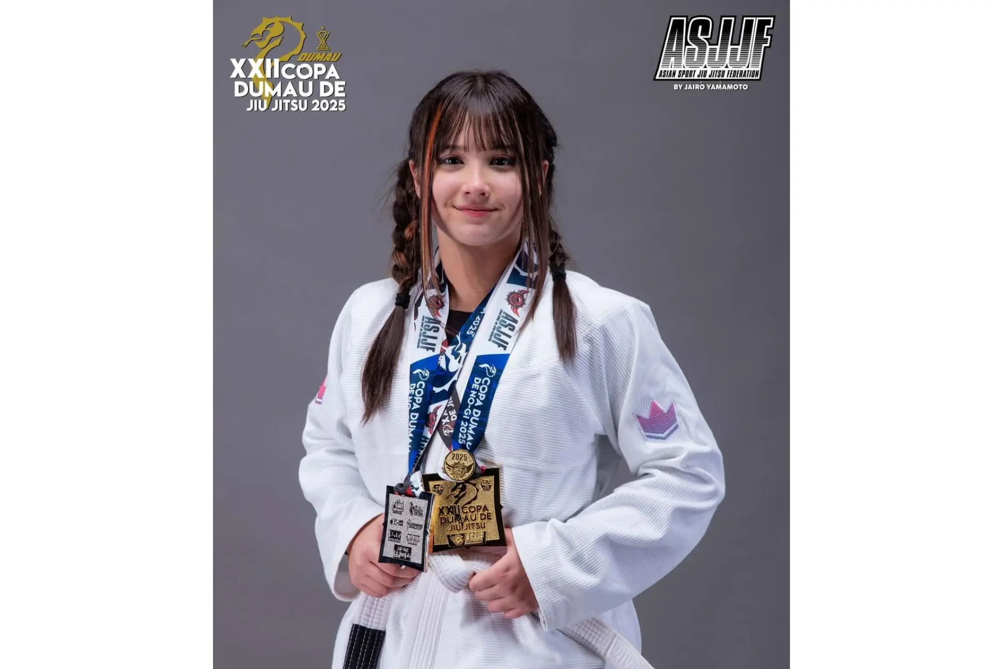 Jovem atleta de jiu jitsu vestindo gi branco, segurando medalhas da XXII Copa DUMAU de Jiu Jitsu 2025, sorrindo para a câmera. De Paranaguá para o Mundo: Mariê Ocubo vence campeonato de Jiu-Jítsu no Japão