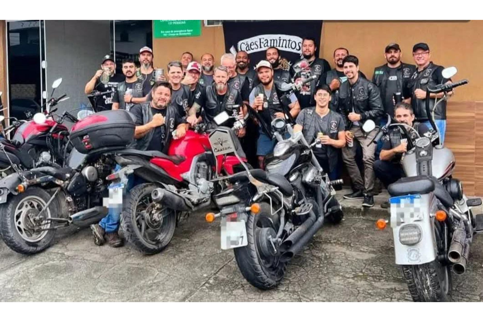 Grupo de motociclistas reunidos, exibindo suas motos e celebrando em um evento social. Estão todos vestidos com jaquetas e sorrindo para a foto.