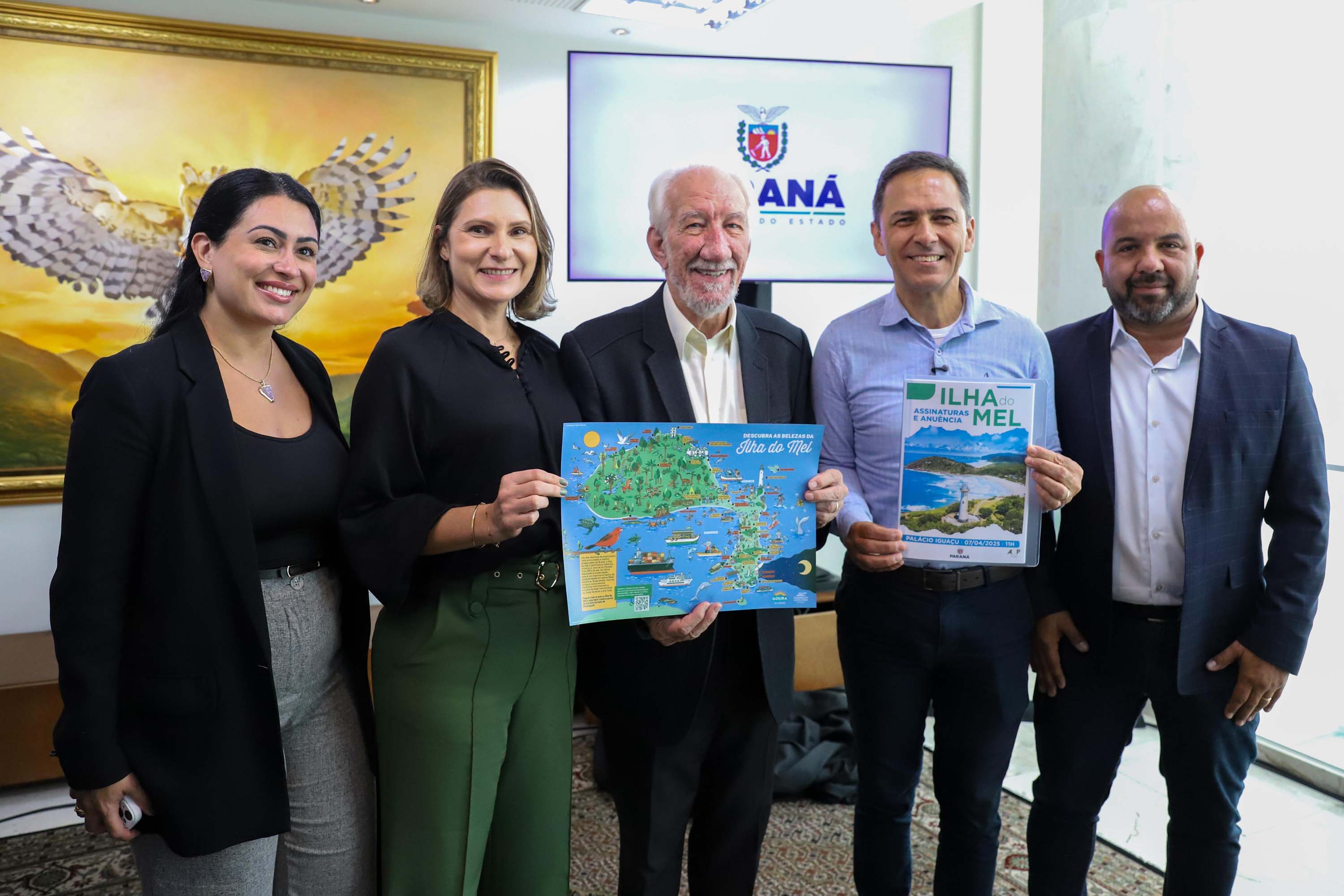 Grupo de pessoas apresentando materiais promocionais sobre Ilha do Mel e estratégias turísticas para o Paraná, destacando a beleza natural da região. Novo marco regulatório da Ilha do Mel avança com instituição de comitê gestor