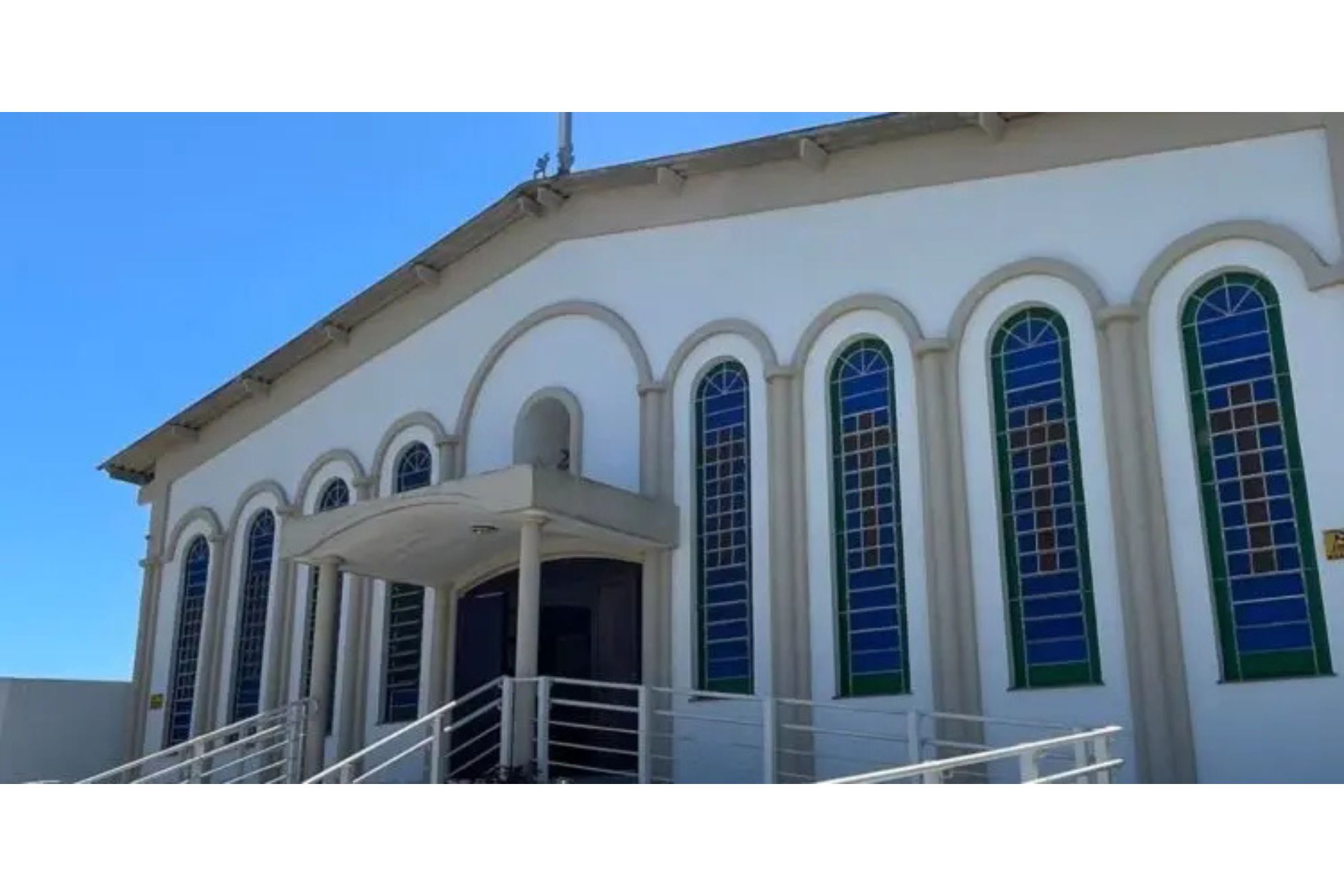 Igreja de estilo neoclássico com janelas coloridas, localizada em ambiente claro e ensolarado, ideal para eventos religiosos e celebrações. Paróquia São João Batista promove o Bazar da Pechincha