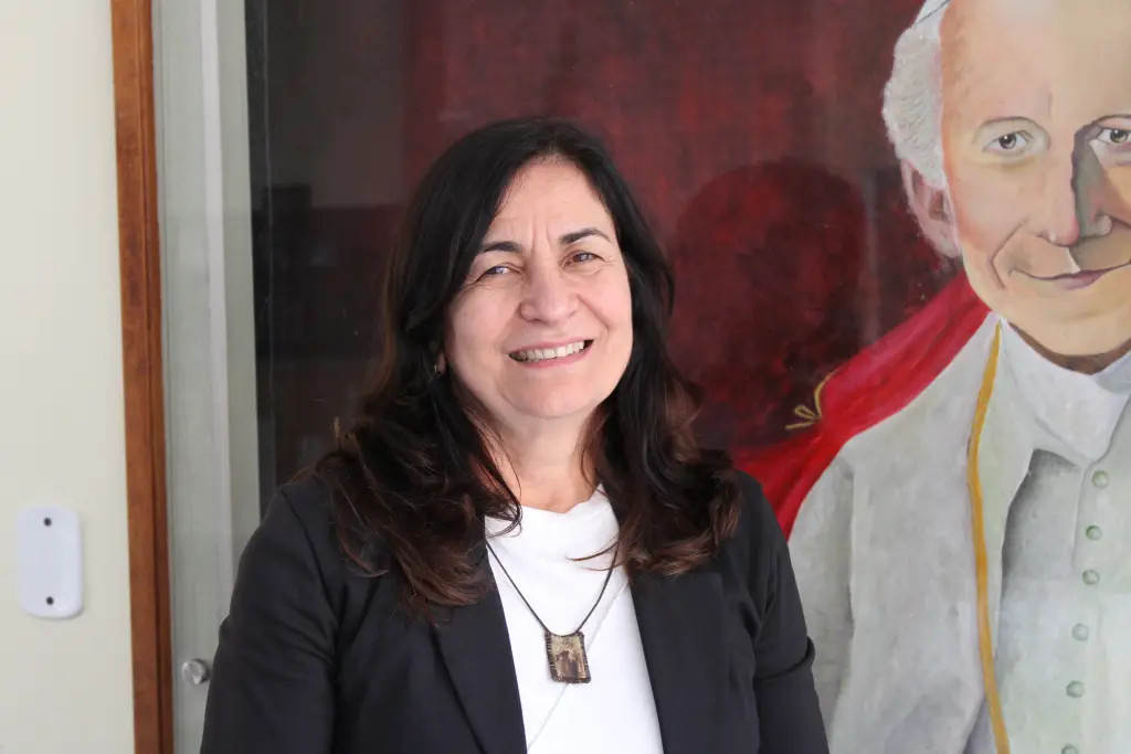 Pastoral "Visíveis para Cristo" realiza ações de apoio, fé e reinserção social com moradores em situação de rua de Paranaguá 1 Imagem de uma mulher sorrindo em frente a um retrato de um papa, simbolizando a cultura e a fé católica. Pastoral "Visíveis para Cristo" realiza ações de apoio, fé e reinserção social com moradores em situação de rua de Paranaguá