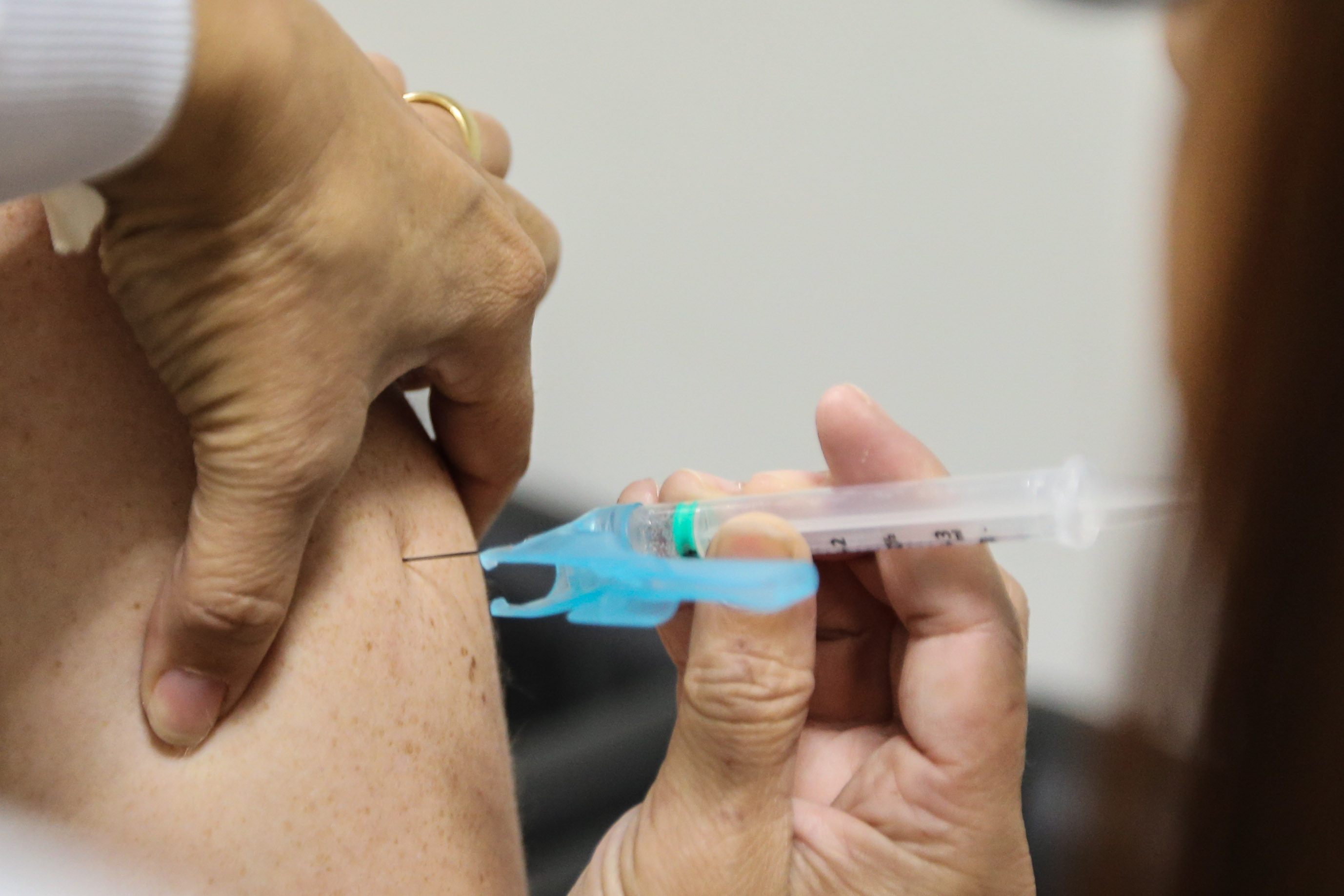 A imagem mostra o momento da aplicação de uma injeção em um braço, ressaltando a importância da vacinação para a saúde. Saúde reforça importância da vacina com circulação de doenças respiratórias no Paraná