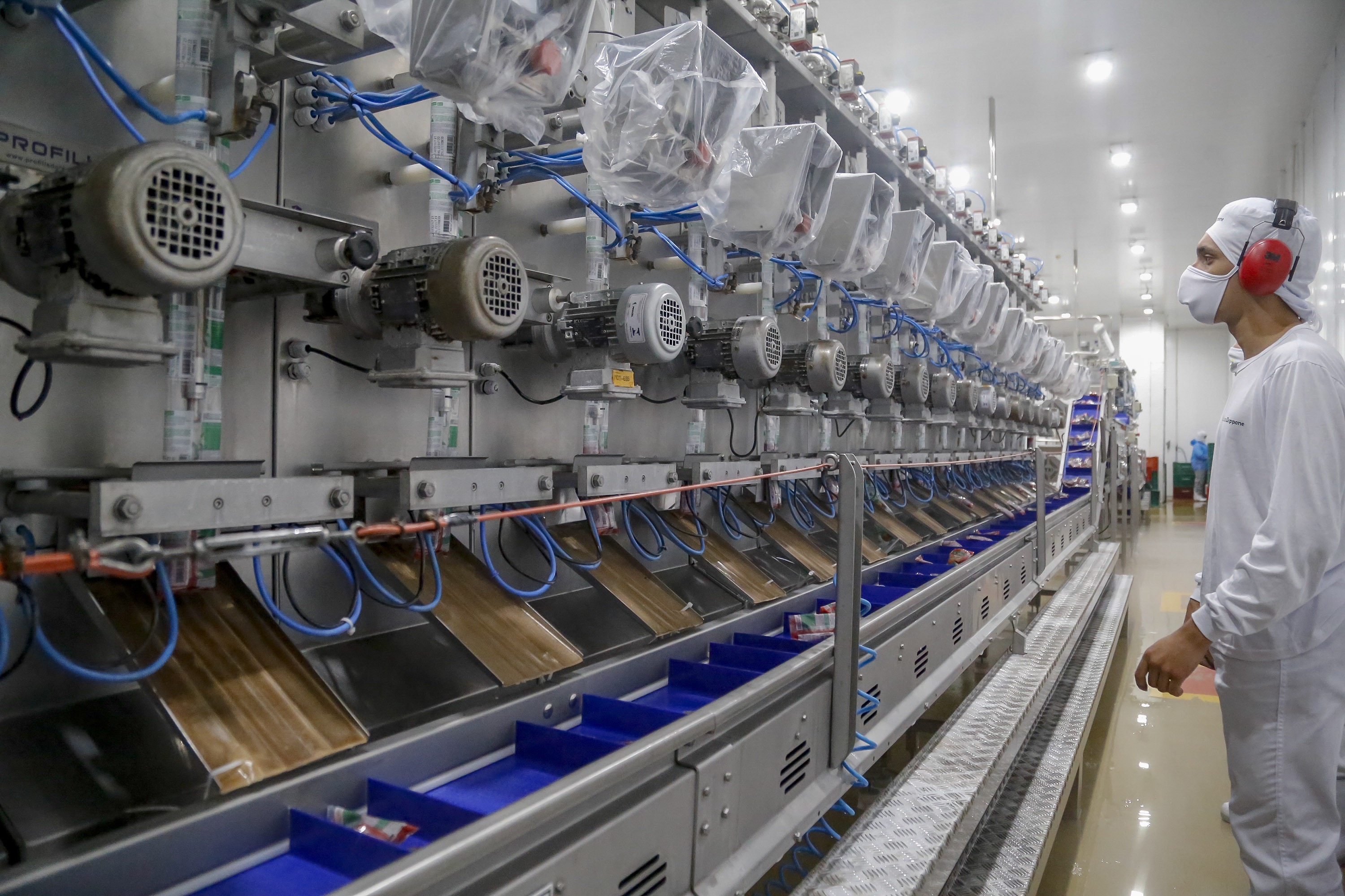 Imagem de um operário em uma linha de produção moderna, observando maquinários industriais em uma fábrica. A foto destaca o ambiente de trabalho automatizado e a tecnologia utilizada. Mais de 300 cidades do Paraná registraram saldo positivo na geração de empregos em 2025