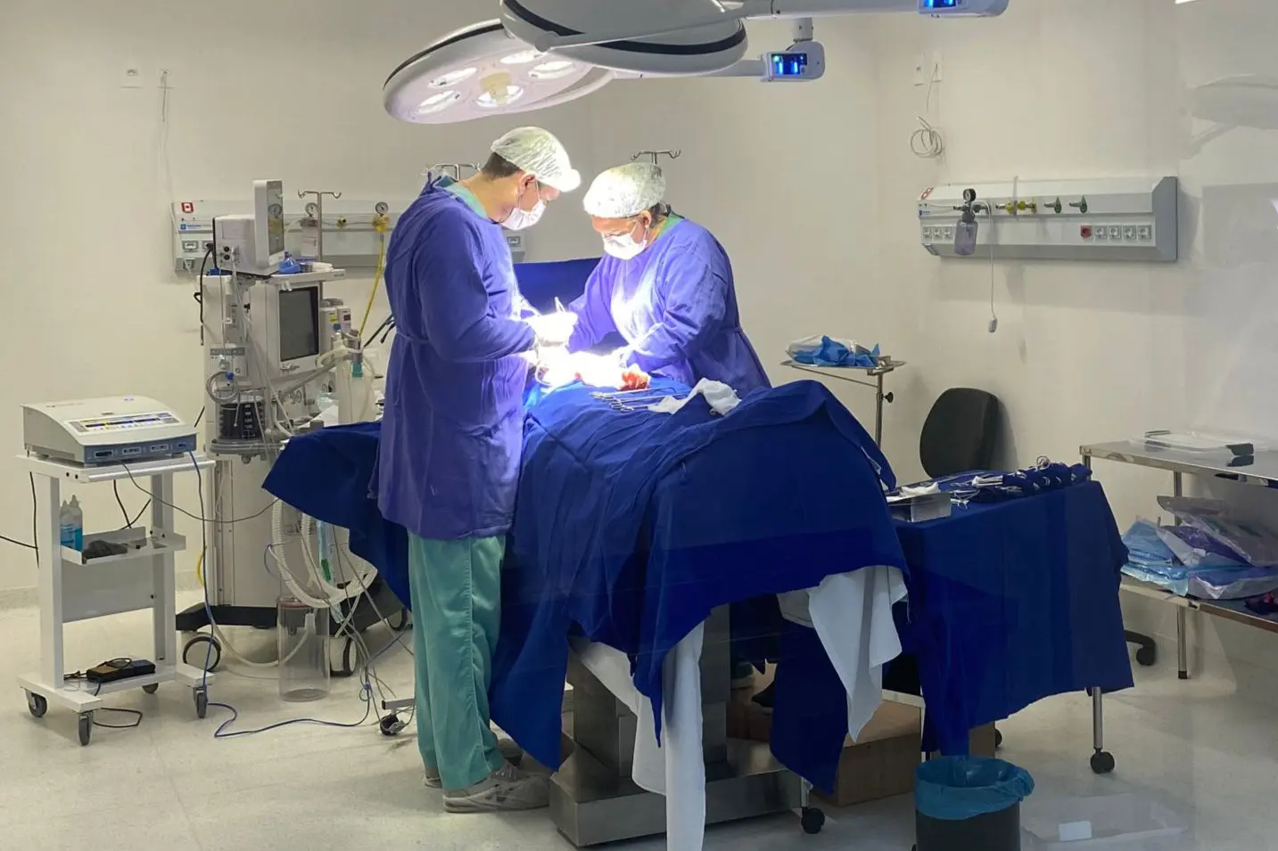 Profissionais realizando uma cirurgia em um ambiente hospitalar, com foco no cuidado e técnica médica, rodeados por equipamentos de tecnologia avançada. Com investimento bilionário, Paraná faz mais de 2 mil cirurgias eletivas por dia