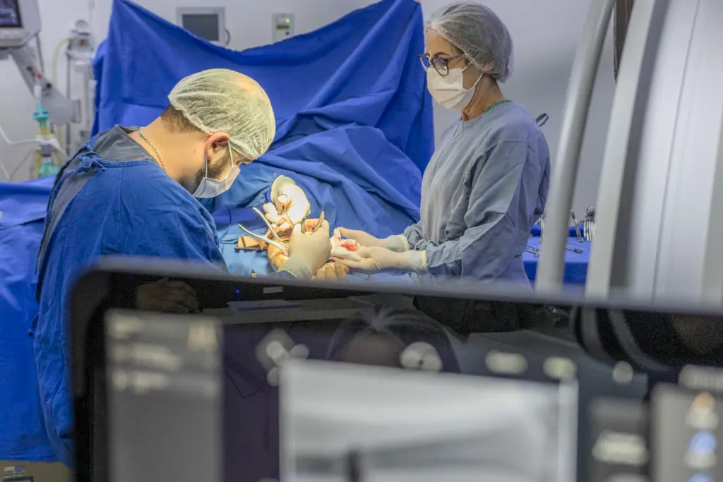 Com investimento bilionário, Paraná faz mais de 2 mil cirurgias eletivas por dia 1 Dois profissionais de saúde em um ambiente cirúrgico, utilizando equipamentos médicos e focados em um procedimento. A imagem retrata a complexidade da cirurgia. Com investimento bilionário, Paraná faz mais de 2 mil cirurgias eletivas por dia