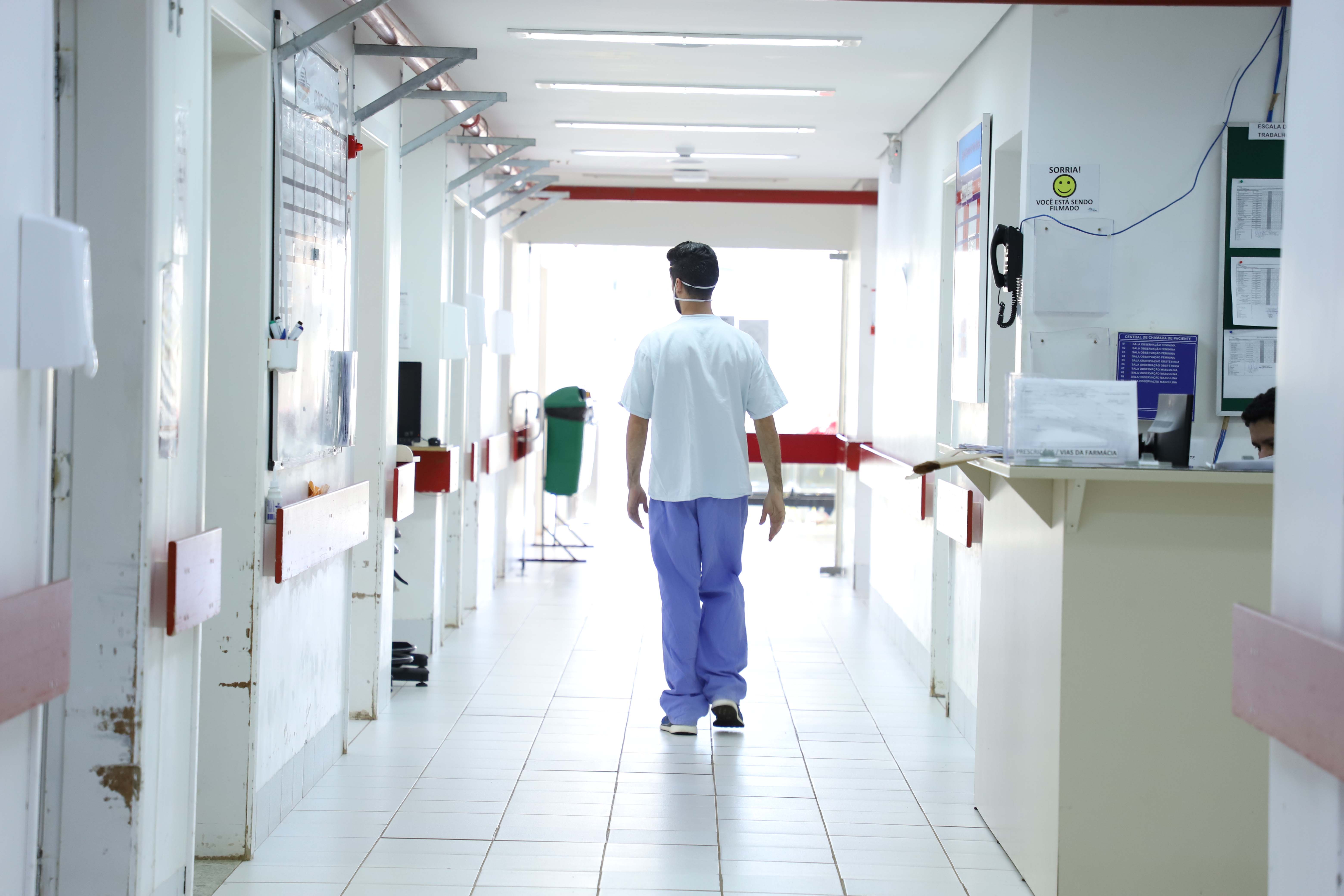 Imagem de um profissional de saúde caminhando por um corredor de hospital, representando a rotina dos trabalhadores da saúde. Mais Médicos: novo ciclo abre 158 vagas em 106 municípios do Paraná