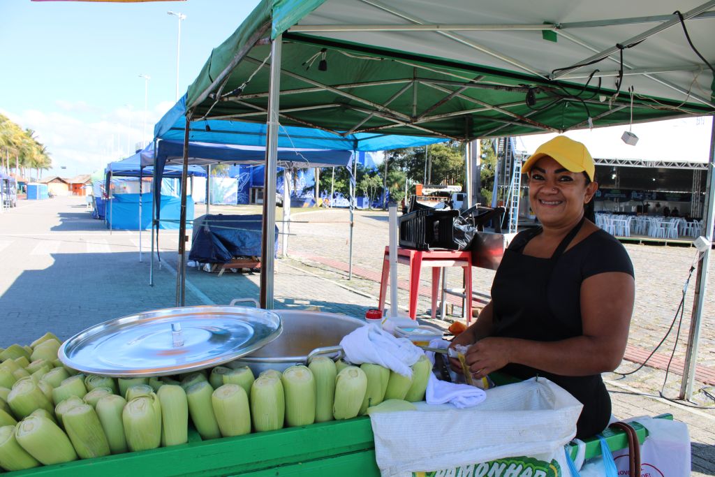 Festa Nacional da Tainha em Paranaguá movimenta o comércio local e contribui para o aumento das vendas de comerciantes 3 Carol Lira é ambulante e está sempre presente nas festas de Paranaguá, comercializando seu milho (Foto: Folha do Litoral News)