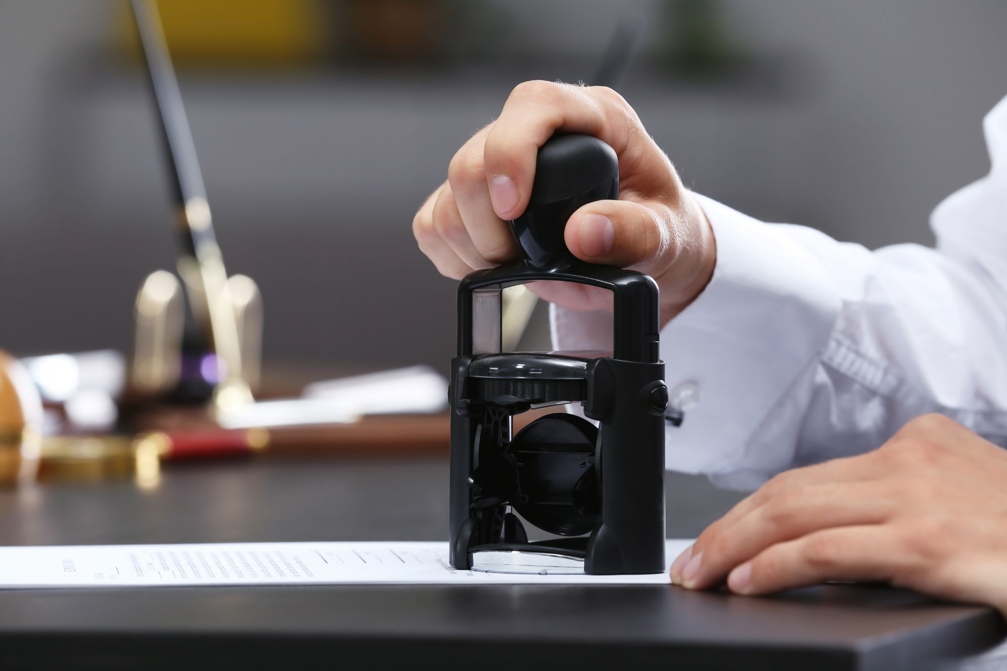 Pessoa usando um carimbo para assinar documentos no escritório, símbolo de autorização e formalidade. Lei da Desburocratização: o que muda para o cidadão com a Lei n.º 13.726/2018