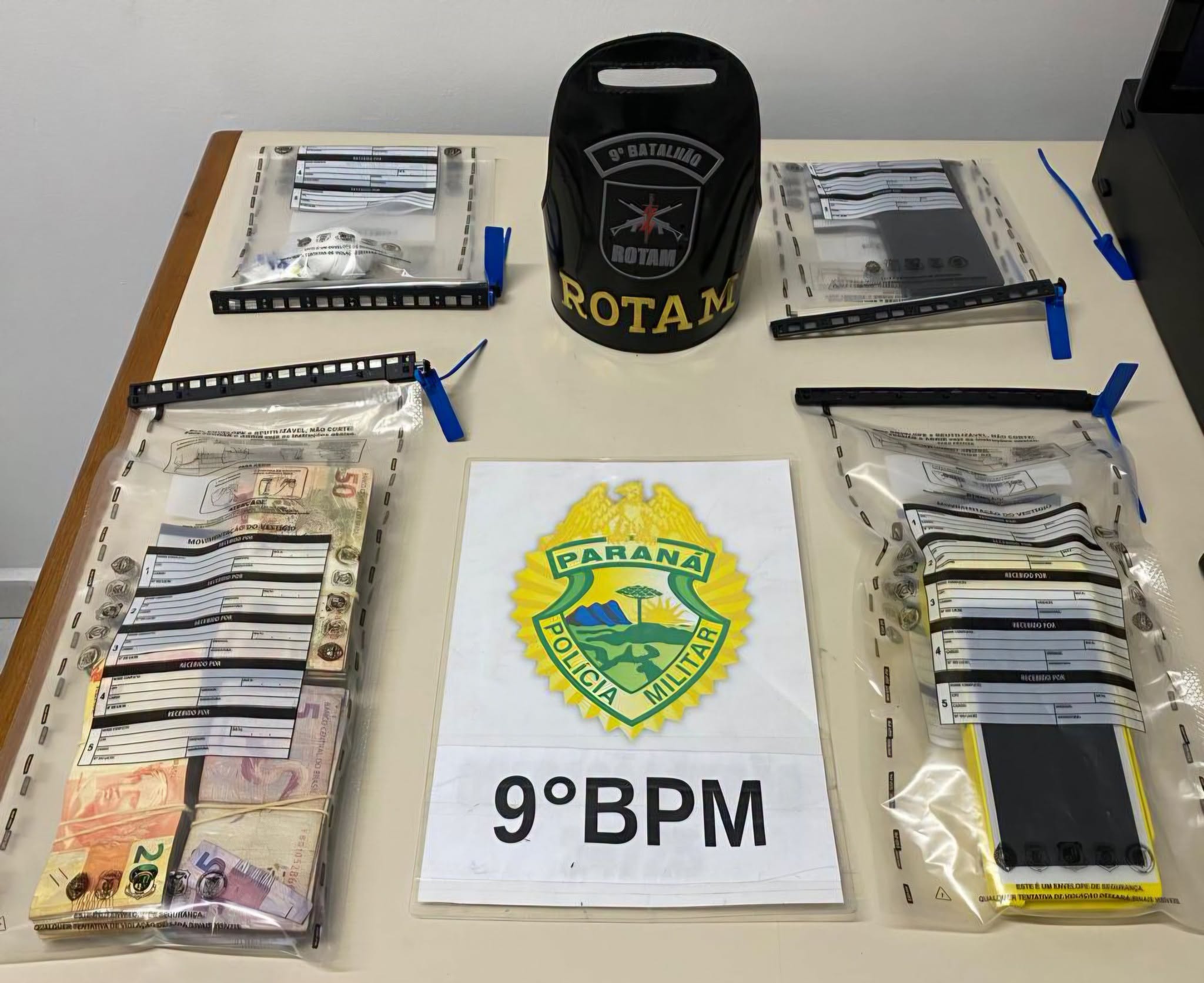 ROTAM prende rapaz que comercializava entorpecentes no portão de uma casa na Vila Cruzeiro 1 Foram apreendidas porções de cocaína, dinheiro trocado e uma máquina de cartão – Foto: PMPR